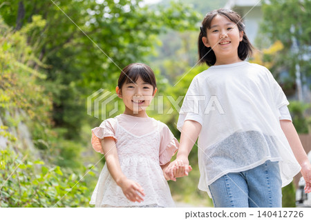 Two smiling girls walking hand in hand. Two smiling girls walking hand in hand. 140412726