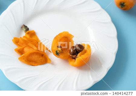 Background material featuring irregularly shaped, organic, fully ripened loquats (peeled). 140414277