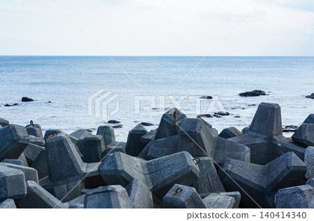 A view of the calm blue sea lined with breakwater blocks and the vast horizon. 140414340