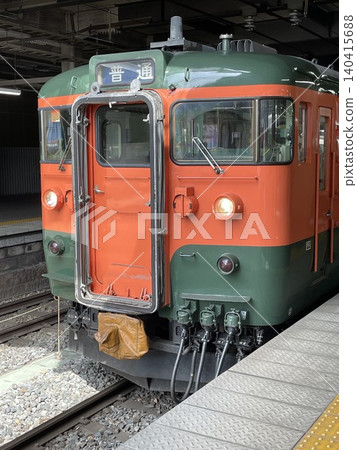 A close-up of the front of the Shinano Railway 115 series S3 train in Shonan colors, stopped at JR Nagano Station. A close-up of the front of the Shinano Railway 115 series S3 train in Shonan colors, stopped at JR Nagano Station. 140415688
