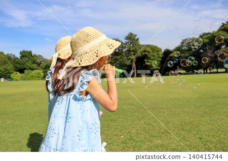 夏日公園裡,兩姊妹正玩著肥皂泡,她們的背影十分有趣。 夏日公園裡,兩姊妹正玩著肥皂泡,她們的背影十分有趣。 140415744