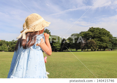 在夏日公園裡,一個小女孩在廣闊的藍天下玩肥皂泡,玩得不亦樂乎。 在夏日公園裡,一個小女孩在廣闊的藍天下玩肥皂泡,玩得不亦樂乎。 140415746