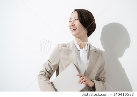 一位手持筆記型電腦的女商人,面帶微笑,回頭望向前方——一張很酷的上半身肖像照。 一位手持筆記型電腦的女商人,面帶微笑,回頭望向前方——一張很酷的上半身肖像照。 140416558