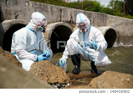 Researcher in hazmat suit collecting contaminated water sample Researcher in hazmat suit collecting contaminated water sample 140416902