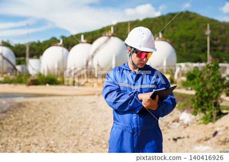 Caucasian engineer inspecting valves at an oil refinery plant 140416926