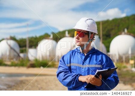 Caucasian engineer inspecting valves at an oil refinery plant Caucasian engineer inspecting valves at an oil refinery plant 140416927