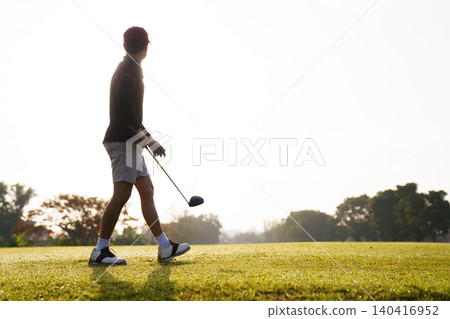 Male golfer carrying driver walking to blue tee box on tee off green Male golfer carrying driver walking to blue tee box on tee off green 140416952