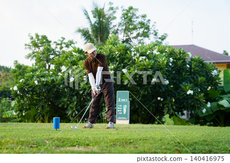 Asian male golfer preparing to swing at blue tee box Asian male golfer preparing to swing at blue tee box 140416975