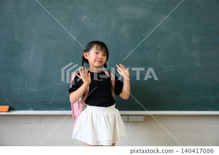 一名一年級女生背著書包，在教室黑板前張開雙臂微笑。 140417086