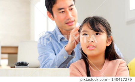 Image of a father tying his daughter's hair Image of a father tying his daughter's hair 140417279