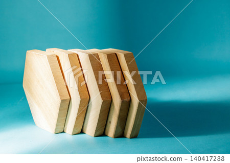 A neat row of five hexagonal wooden coasters standing upright side-by-side casting a shadow on a bright cyan background. High Quality Photo 140417288
