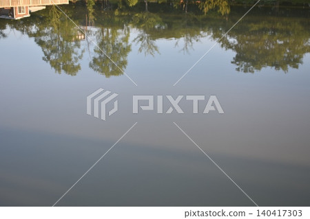 The city and the lush green landscape reflected on the calm surface of the water. 140417303