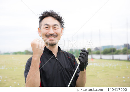 A portrait of a smiling male golfer holding a golf club, looking directly at the camera and making a victory pose. A portrait of a smiling male golfer holding a golf club, looking directly at the camera and making a victory pose. 140417900