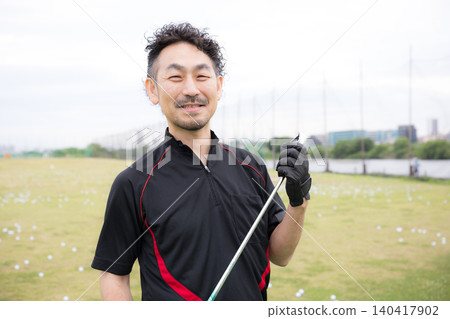 A portrait of a smiling male golfer holding a golf club, looking directly at the camera and smiling while practicing golf. A portrait of a smiling male golfer holding a golf club, looking directly at the camera and smiling while practicing golf. 140417902