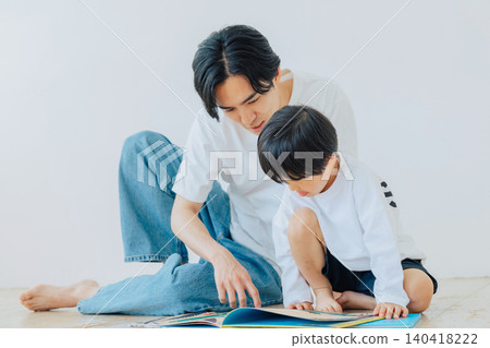 A boy reading a picture book with his father. A boy reading a picture book with his father. 140418222