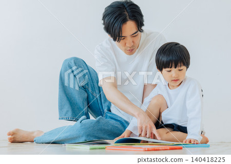 A boy reading a picture book with his father. A boy reading a picture book with his father. 140418225