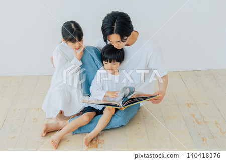 A brother and sister reading a picture book together with their father. A brother and sister reading a picture book together with their father. 140418376