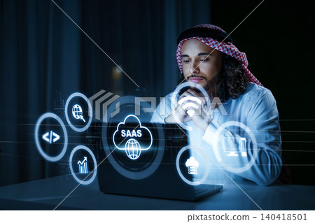Man using laptop to explore SaaS concepts in a dark room at night 140418501