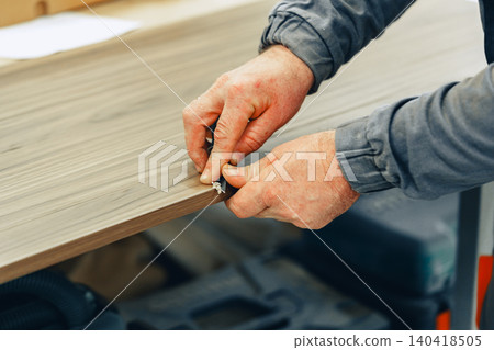 Worker prepares furniture in a workshop during a busy day of crafting Worker prepares furniture in a workshop during a busy day of crafting 140418505