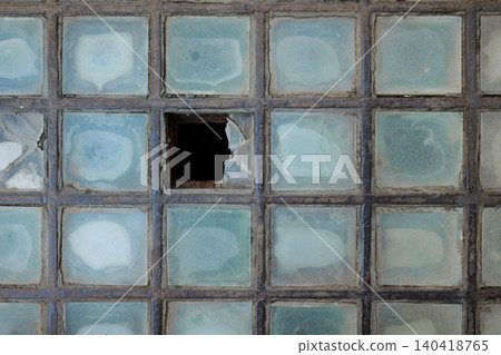 Top down view of a weathered iron grid with translucent square glass blocks and one missing tile 140418765
