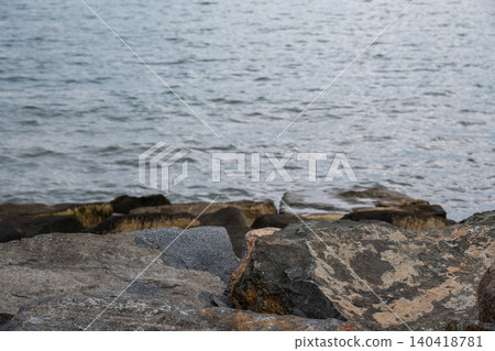 Rocks sit along the water's edge while waves gently flow in and out. Rocks sit along the water's edge while waves gently flow in and out. 140418781
