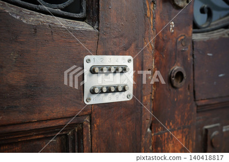 Close-up of a silver push button mechanical code lock installed on a weathered brown wood door surface Close-up of a silver push button mechanical code lock installed on a weathered brown wood door surface 140418817