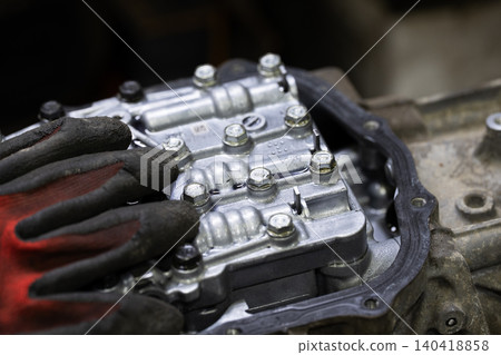 Close up of a textured mechanic glove resting on a complex metal hydraulic gearbox valve body Close up of a textured mechanic glove resting on a complex metal hydraulic gearbox valve body 140418858