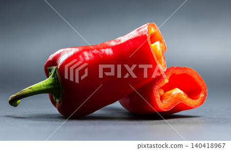 Studio slice shot of a crisp red sweet pepper sliced in half, showing internal hollow cavity and glossy skin Studio slice shot of a crisp red sweet pepper sliced in half, showing internal hollow cavity and glossy skin 140418967