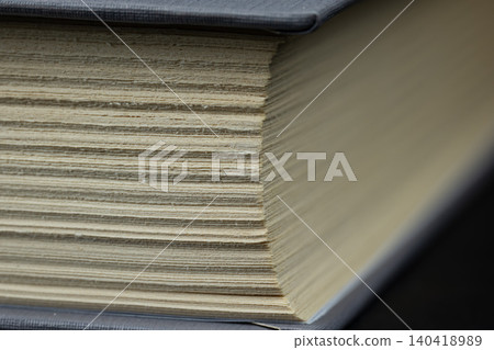 Detailed side view of textured paper pages from an old hardcover book with shallow depth of field Detailed side view of textured paper pages from an old hardcover book with shallow depth of field 140418989
