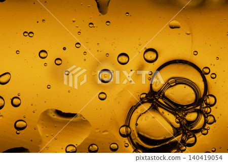 Macro shot of textured amber liquid with floating oil droplets and swirling dark ink patterns Macro shot of textured amber liquid with floating oil droplets and swirling dark ink patterns 140419054