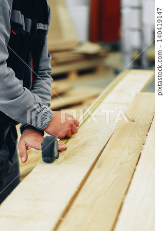 Craftsman measures wood in a furniture workshop during a wood working session Craftsman measures wood in a furniture workshop during a wood working session 140419147