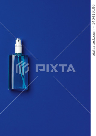 Clear bottle of liquid on a blue background during daytime in a simple setting Clear bottle of liquid on a blue background during daytime in a simple setting 140419196