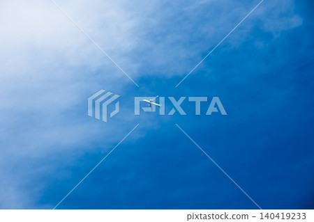A plane travels in the sky surrounded by clouds on a clear day. A plane travels in the sky surrounded by clouds on a clear day. 140419233