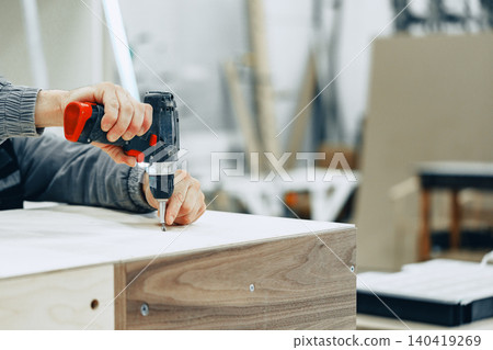 Crafting furniture in a workshop with a power drill in hand during the day Crafting furniture in a workshop with a power drill in hand during the day 140419269