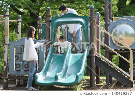 A family playing on the slide in the park A family playing on the slide in the park 140419287