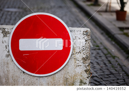 Close-up of a circular red stop sign with a white horizontal bar on a textured concrete base Close-up of a circular red stop sign with a white horizontal bar on a textured concrete base 140419352