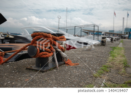 Close-up of a black metal bollard secured with heavy orange rope at a commercial boat dock Close-up of a black metal bollard secured with heavy orange rope at a commercial boat dock 140419407