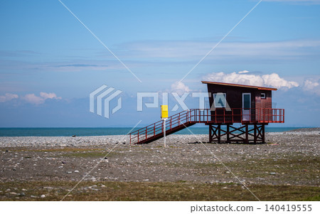 Small red wooden station on stilts located on a vast stone beach by the sea Small red wooden station on stilts located on a vast stone beach by the sea 140419555