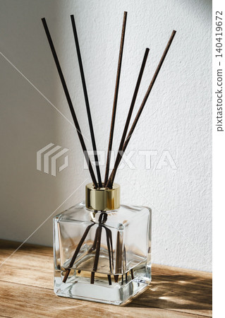 Decorative fragrance diffuser on wooden surface near wall in bright light Decorative fragrance diffuser on wooden surface near wall in bright light 140419672