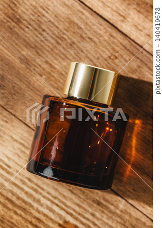 Dark glass bottle of fragrance placed on wooden surface with warm light Dark glass bottle of fragrance placed on wooden surface with warm light 140419678