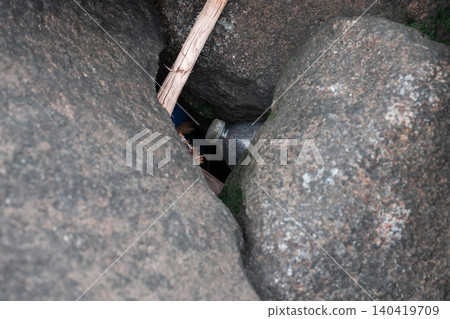 High-angle shot of a plastic bottle and debris trapped in dark, mossy rock crevices High-angle shot of a plastic bottle and debris trapped in dark, mossy rock crevices 140419709