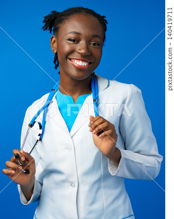 Young doctor smiles while holding a pen and a stethoscope in a bright setting 140419711