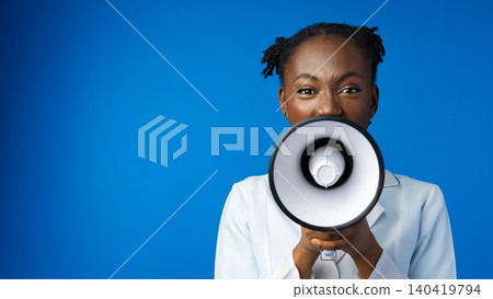 Woman with a megaphone speaks in front of a blue background Woman with a megaphone speaks in front of a blue background 140419794