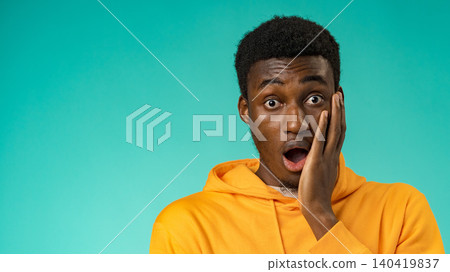 Person shows surprise while standing against a bright blue background in casual clothing Person shows surprise while standing against a bright blue background in casual clothing 140419837