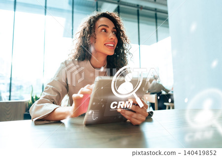 Woman using tablet to learn about customer relationship management in office during work hours 140419852