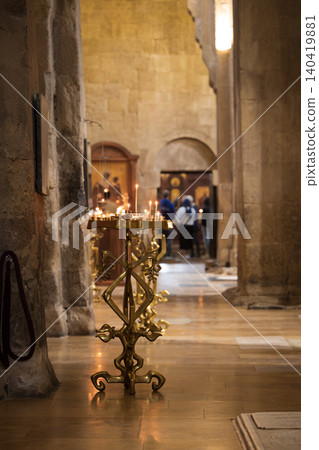 View of the long nave of an ancient orthodox cathedral with golden candle stands and icons View of the long nave of an ancient orthodox cathedral with golden candle stands and icons 140419881