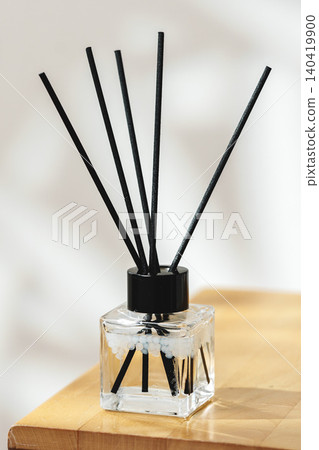 Fragrance diffuser with black sticks on wooden table in soft light Fragrance diffuser with black sticks on wooden table in soft light 140419900