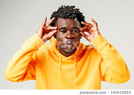 Man poses with fingers by his head and makes a unique facial expression in a studio setting 140419958