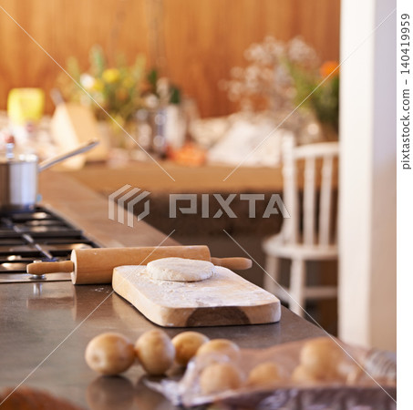 Dough, pin and wooden board in kitchen with ingredients on counter for baking and cooking with pastry for bread with recipe. Flour, wheat and potatoes with stove and pot for food with vegetables 140419959