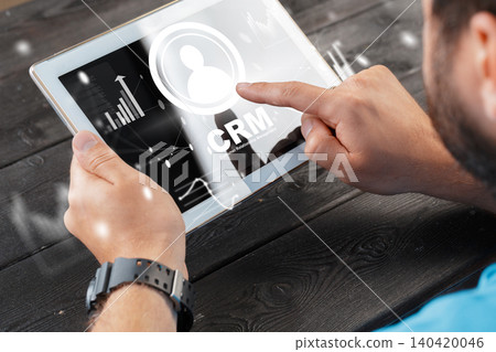 Holding a tablet that displays CRM data and analytics for business use Holding a tablet that displays CRM data and analytics for business use 140420046